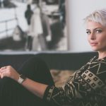 woman sitting on sofa holding eyeglasses