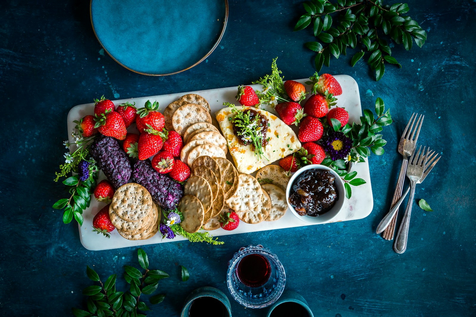 a platter of crackers, strawberries, and fruit