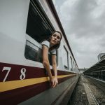 woman's head and hands outside train under cloudy sky during daytime