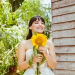 a woman in a wedding dress holding a sunflower