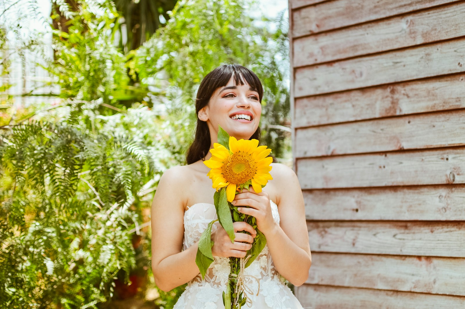 a woman in a wedding dress holding a sunflower