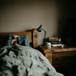 a person laying in bed under a blanket