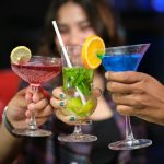 a group of people holding up wine glasses filled with different types of drinks