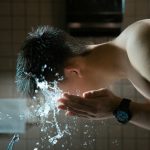person washing face with water